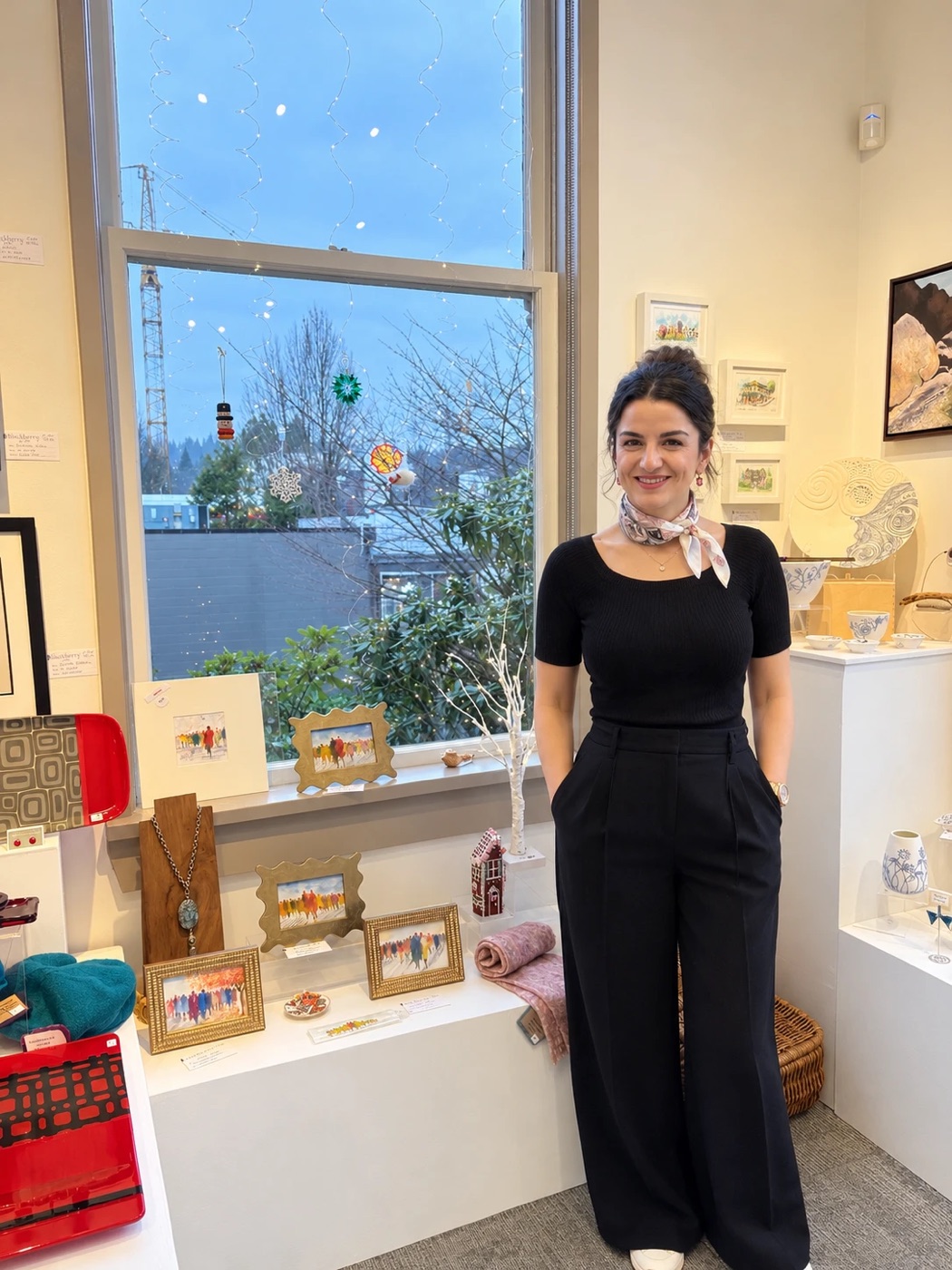 Sepideh Saba in a gift shop, beside a display of her framed watercolour paintings.